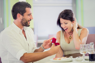 Obraz na płótnie Canvas young romantic man proposal to girlfriend at restaurant