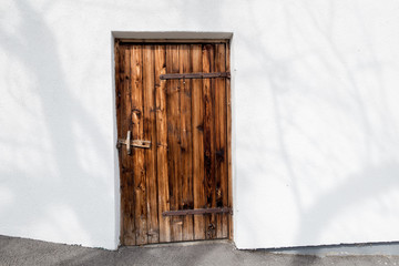 dunkle alte Holztür in einer weißen Hauswand