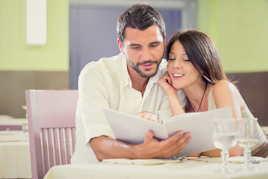 Young romantic brunette couple reading menu  at restaurant