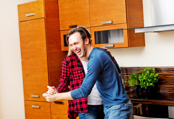 Fototapeta na wymiar Young couple dancing and having fun in the kitchen 