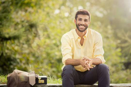 Young beautiful smiling business man portrait outdoor in a park