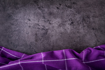 Top view of checkered kitchen purple tablecloth on concrete - stone - marble -  wooden background. Free space for your text or products.