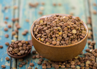Raw lentils in bowl on a blue wooden table