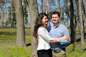 Happy young family spending time outdoors in a park on a spring day with blue sky in background. Spending time together having fun and smiling. Married couple. 