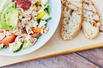 Colourful salad with fresh ingredients alongside sliced bread