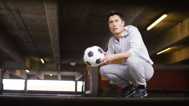 Young man bouncing a football as he looks towards light
