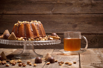 cake, candy, nuts and cup on old wooden background