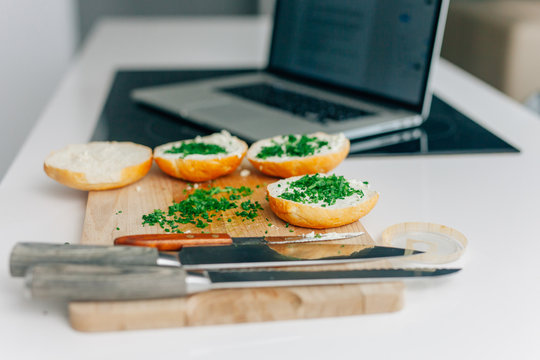 Healthy sandwiches with white cheesse and chive. Knifes and laptop on the table.