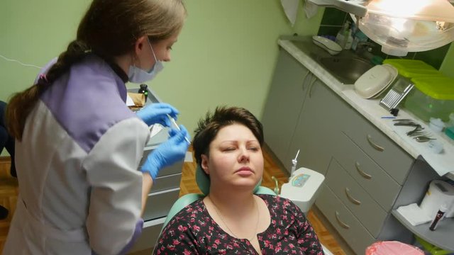 4k Dentist examining a patients teeth under bright light at the dental clinic