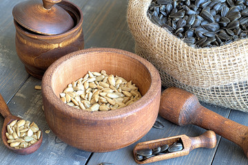  Sunflower seeds.   Sunflower seeds in a wooden crockery peeled and unpeeled in a bag on a wooden background.