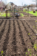 plowed country garden and tiller in village