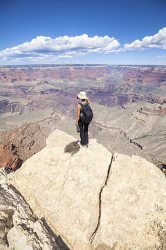 Young woman standing on the edge of a cliff and taking pictures of the Grand Canyon, hobby and adventure concept.