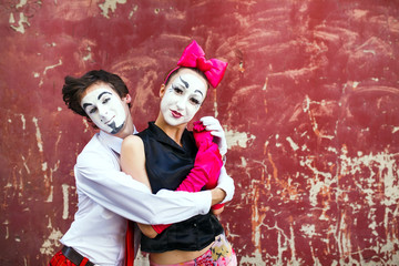 Couple mimes cute pose in front of a red wall.