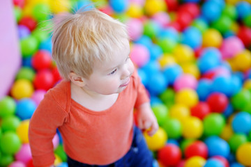 Happy toddler boy playing in ball pit