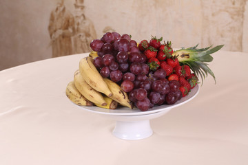 strawberries, bananas, pineapple and grapes - fruits on a plate