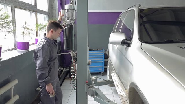 Repairman Pushing Button to Lift the Car