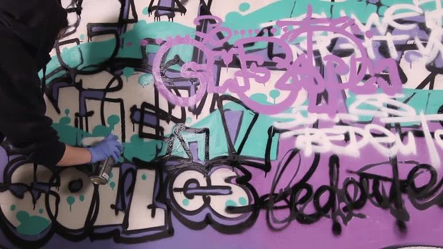 Video shot of a young girl tagging wall with graffiti
