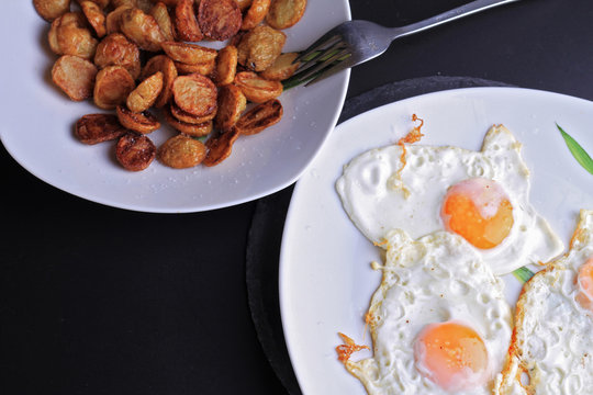 Fried eggs on plate and fried potatoes. High fat and  High cholesterol food