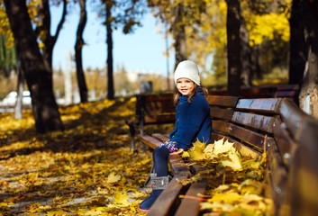 Little girl sitting on a bench in the park