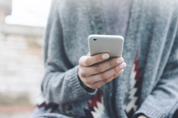 Closeup of female hands using modern smartphone outdoors, young girl using cellphone or typing text message