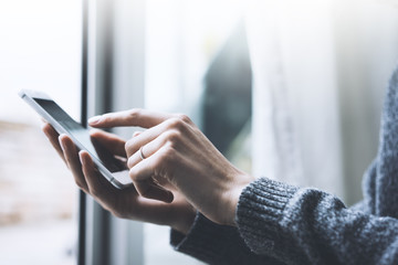 Closeup of female hands using smartphone in interior, woman’s hands using cellphone while working...