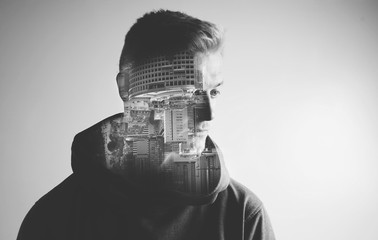 Creative double exposure portrait of young man with modern buildings, monochrome