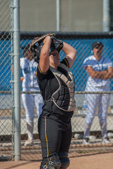 Strong softball player in black uniform lifting her mask between plays. 