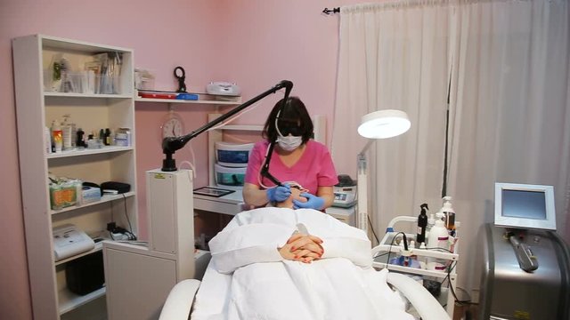 Woman getting laser face treatment in medical spa center, skin rejuvenation concept.Cosmetic surgeon doctor giving fractional CO2 laser skin treatment to the face of a senior female woman patient