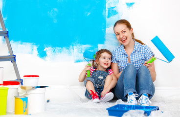 happy family mother and child daughter making repairs, paint wal