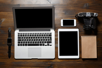 Top view office. On a wooden table lay a tablet computer, a laptop, a phone, a tablet, a notebook...