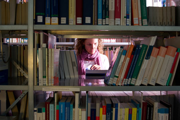 Frau zwischen Bücherregalen, sucht verzweifelt ein Buch 