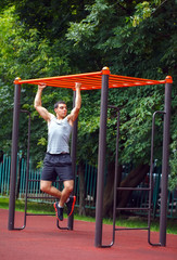 Muscular man doing pull-ups on horizontal bar