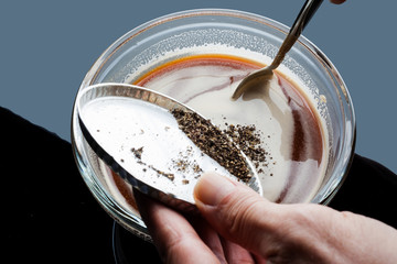 Seasoning tomato sauce in a glass bowl with milled black pepper 