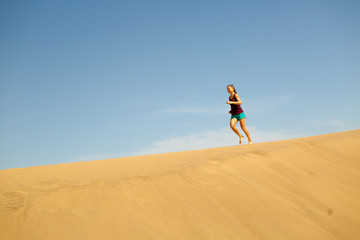 Woman running barefoot on sand desert dunes