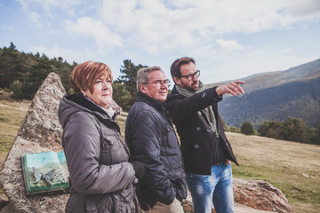 Senior couple with their son taking a walk in the mountain. Son