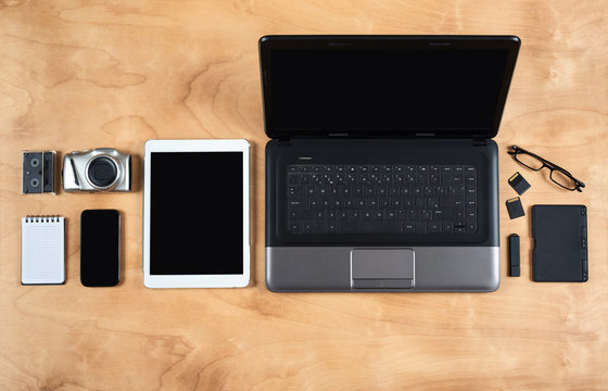 Flat lay of personal office accessories, laptop, notebook, coffee cup  and camera on wood background, top view