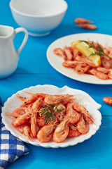 Prepared shrimps on a plate on blue surface.