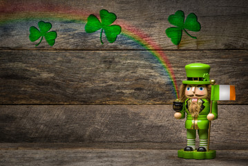 Wooden Irish leprechaun with shamrocks, rainbow, pot of gold and Irish flag on weathered wood...