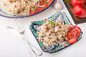 Traditional uzbek pilaf (plov) with tomatoes and red onion