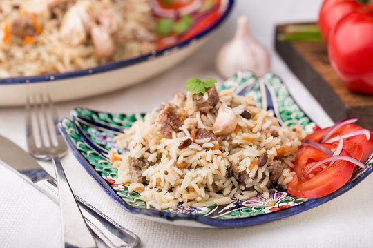 Traditional uzbek pilaf (plov) with tomatoes and red onion