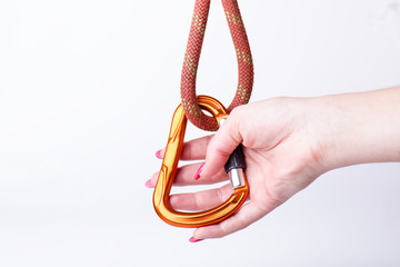 Woman´s hand holding a carabine on a rope. Climbing equipment isolated on a white background. 