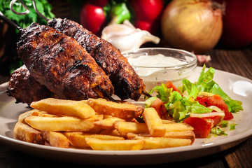 Grilled shish kebab served with fried chips and salad
