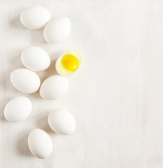 White eggs lined up on a white wooden background
