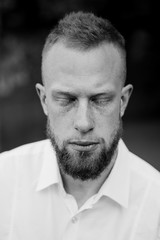 portrait of young red hair man with closed eyes , beard black and white