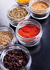 Spices on black background in special jars. Food