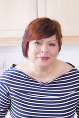 .Happy mature woman smiling in kitchen