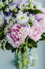 Rich bunch of pink peonies peony and lilac eustoma roses flowers in glass vase on white background. Rustic style, still life.