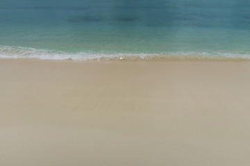 Fototapeta na wymiar Wellen und Wasser Hintergrund mit Strand am Meer in blau, beige, türkis.