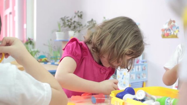 Little girl playing doctors in kindergarten with other children.