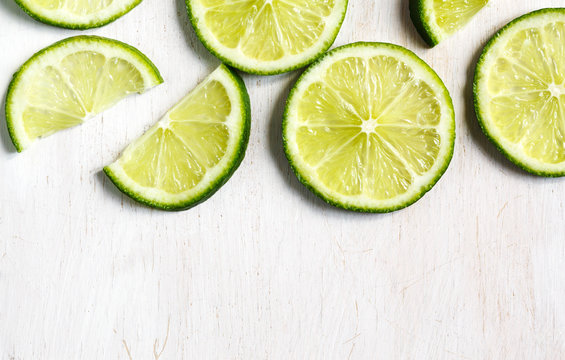 Lime slices on white wooden background